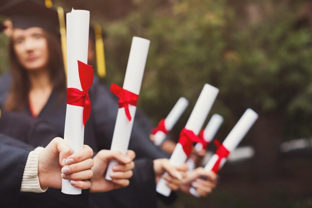 Group of students holding diplomas, copy space